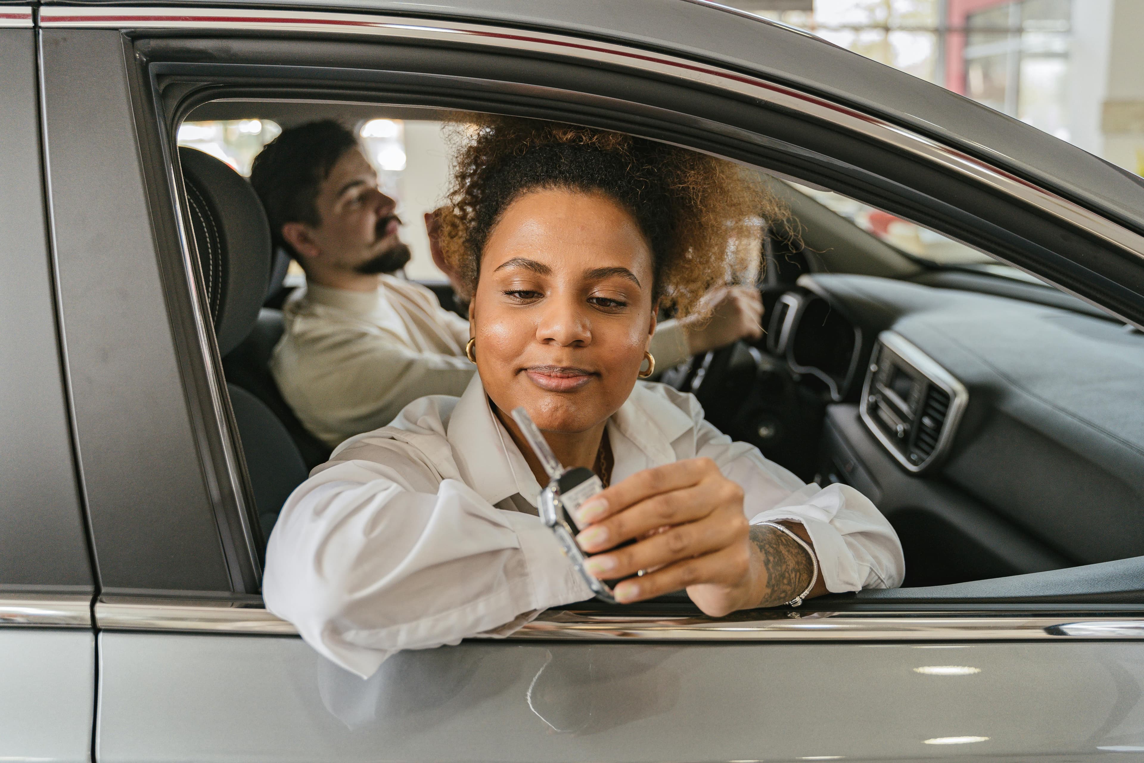 Žena v aute na operatívny leasing ktorá drží v ruke kľúč od auta